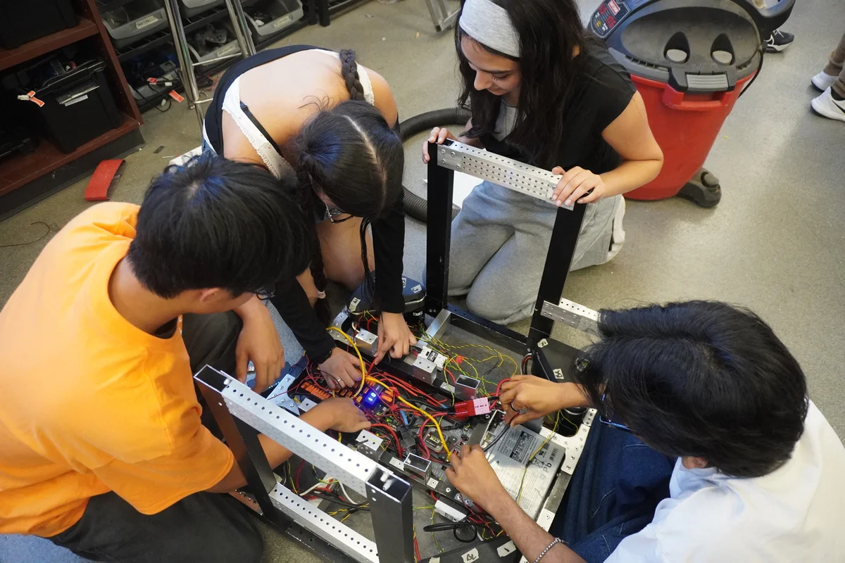 Students working together to assemble a robot mechanism.