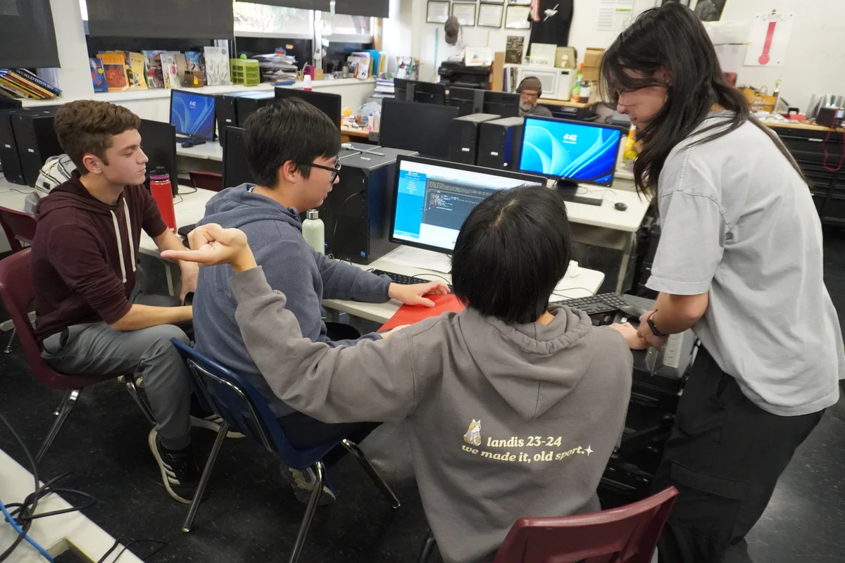 Team members discussing their work around a computer.