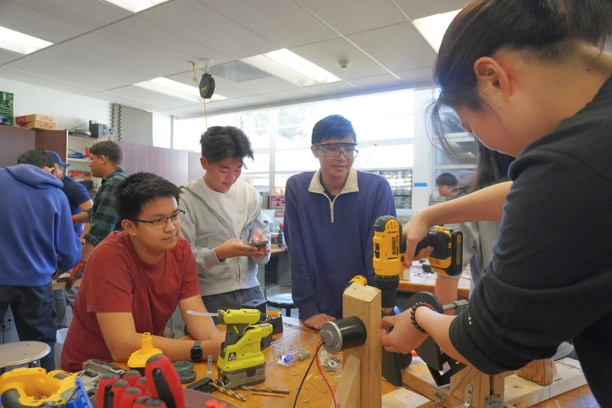Team members building together at a workshop table.